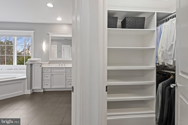 spacious closet featuring sink and dark tile patterned floors