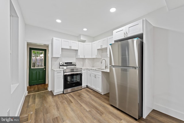 kitchen featuring appliances with stainless steel finishes, white cabinets, and light hardwood / wood-style flooring