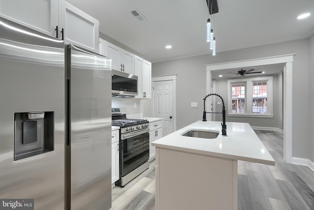 kitchen featuring sink, hanging light fixtures, an island with sink, stainless steel appliances, and white cabinets