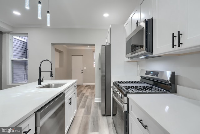 kitchen with appliances with stainless steel finishes, decorative light fixtures, sink, and white cabinets