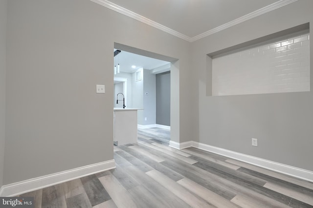 spare room with sink, crown molding, and light wood-type flooring