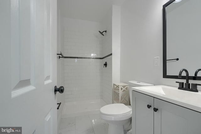 bathroom featuring vanity, toilet, and a tile shower