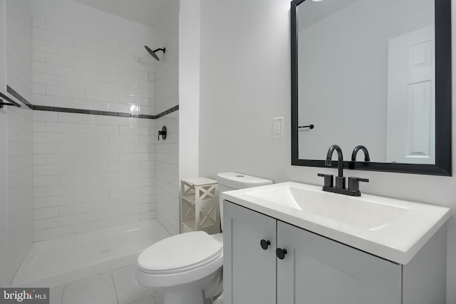 bathroom featuring vanity, toilet, and a tile shower