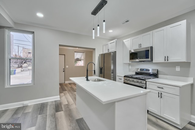 kitchen featuring pendant lighting, appliances with stainless steel finishes, sink, and a center island with sink