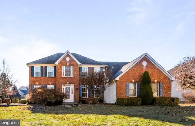 colonial inspired home with brick siding and a front yard