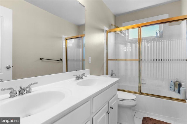 full bath featuring toilet, double vanity, enclosed tub / shower combo, and a sink