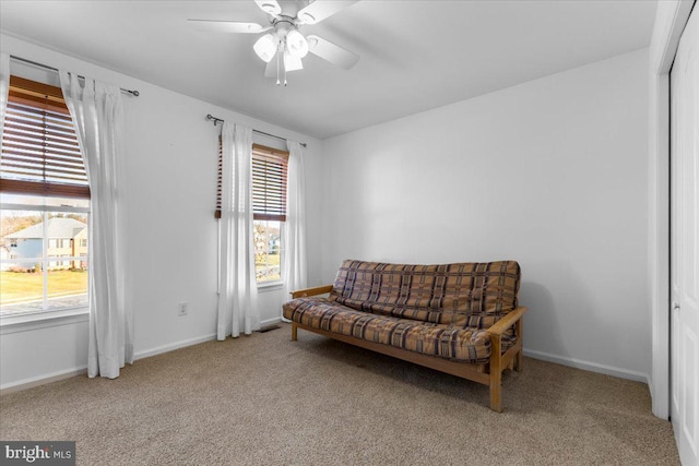 living area featuring light carpet, ceiling fan, and baseboards