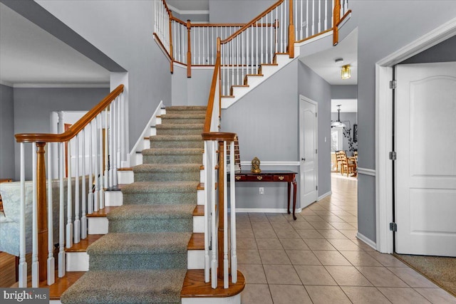 stairway featuring crown molding, tile patterned floors, and a high ceiling