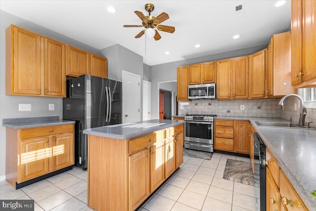 kitchen with decorative backsplash, ceiling fan, a kitchen island, stainless steel appliances, and a sink