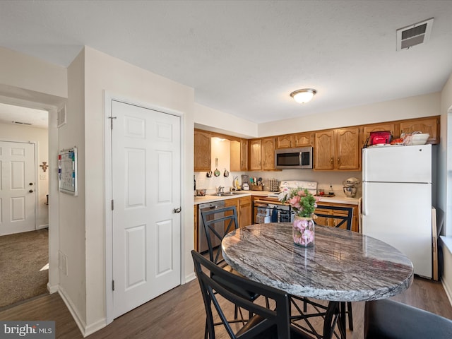 kitchen featuring white fridge, dark hardwood / wood-style floors, dishwashing machine, and stove