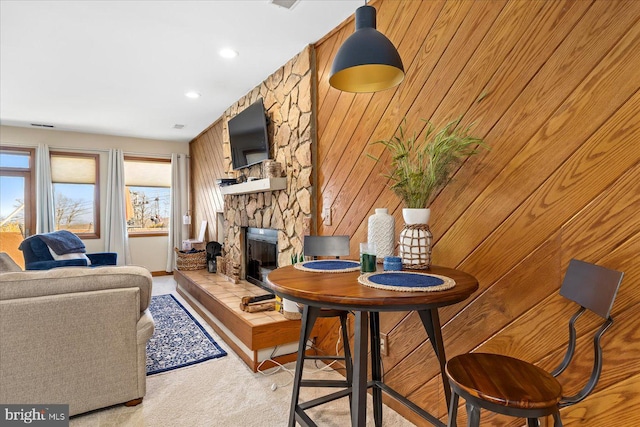 carpeted living room featuring a fireplace and wood walls