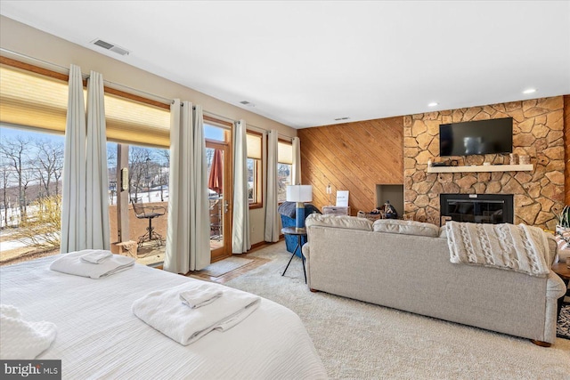 carpeted bedroom with wood walls, a fireplace, and access to outside