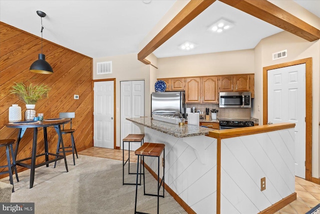 kitchen with pendant lighting, a breakfast bar, stainless steel appliances, a center island, and wood walls