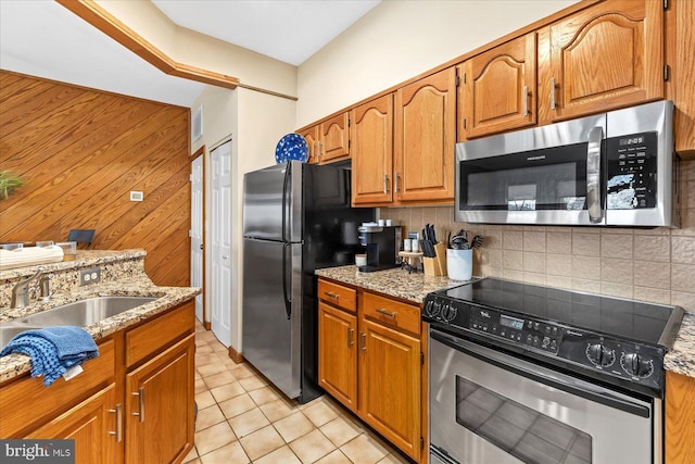 kitchen featuring sink, backsplash, stainless steel appliances, and light stone countertops