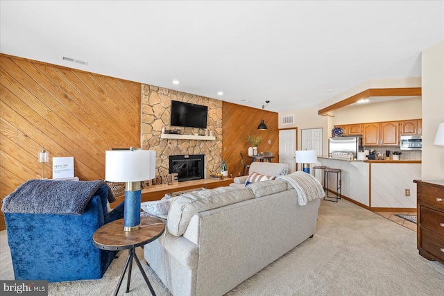 carpeted living room with wooden walls and a fireplace