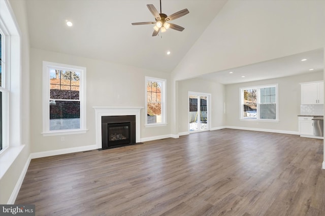 unfurnished living room featuring wood-type flooring, ceiling fan, and high vaulted ceiling