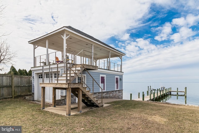 dock area featuring a water view, stairs, fence, and a yard