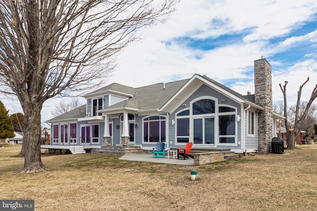 back of property with a shingled roof, a lawn, and a chimney