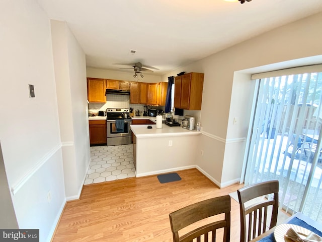 kitchen with kitchen peninsula, electric stove, ceiling fan, light hardwood / wood-style floors, and decorative backsplash