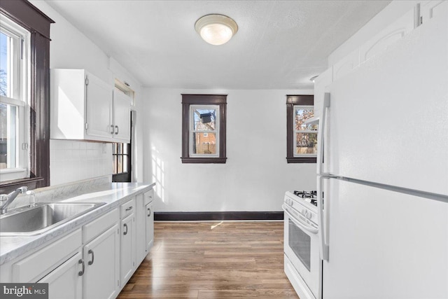 kitchen with sink, white appliances, white cabinetry, tasteful backsplash, and wood-type flooring