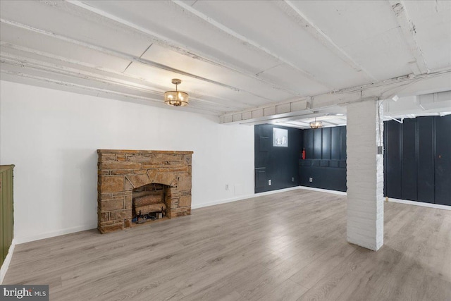 unfurnished living room featuring hardwood / wood-style flooring and a stone fireplace