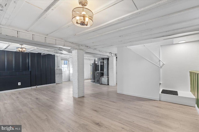 unfurnished living room with a notable chandelier, gas water heater, and light hardwood / wood-style floors