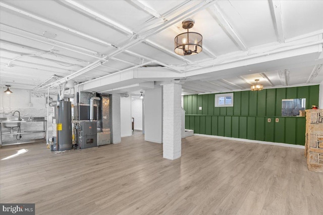 basement with heating unit, sink, light hardwood / wood-style floors, and water heater