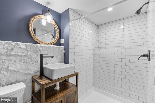 bathroom featuring toilet, sink, and tiled shower