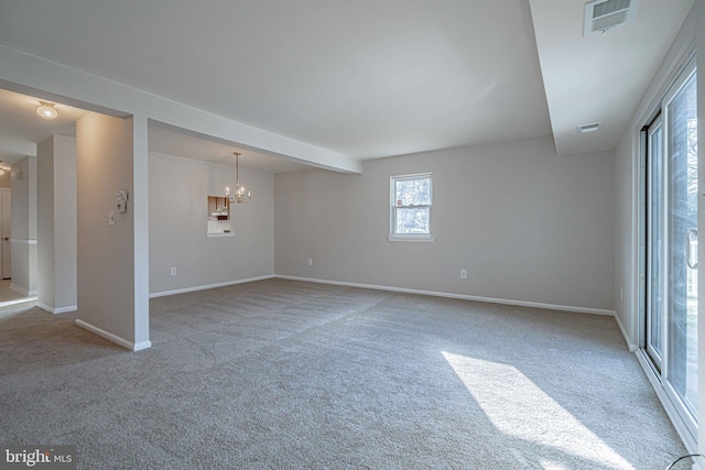 carpeted empty room with an inviting chandelier