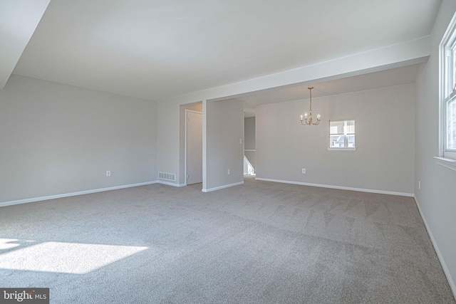 carpeted spare room featuring a notable chandelier