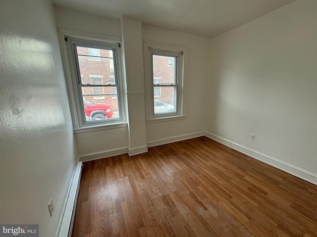 spare room featuring a baseboard heating unit and light wood-type flooring