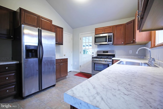 kitchen with lofted ceiling, appliances with stainless steel finishes, and sink