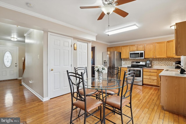 dining area featuring sink, crown molding, light hardwood / wood-style flooring, and ceiling fan