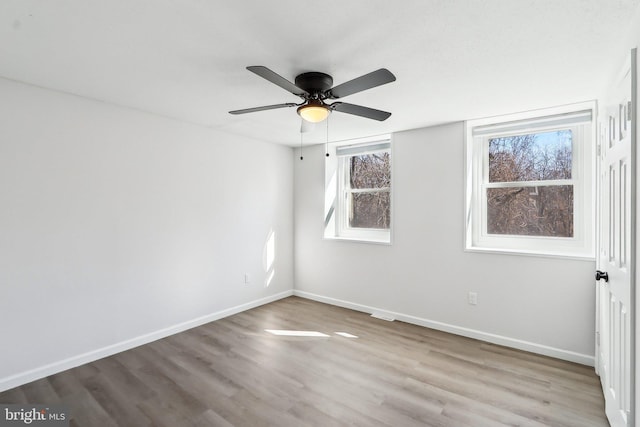 empty room with a ceiling fan, baseboards, and wood finished floors