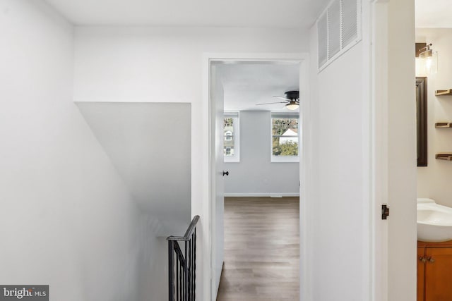 hall featuring wood finished floors, a sink, and visible vents