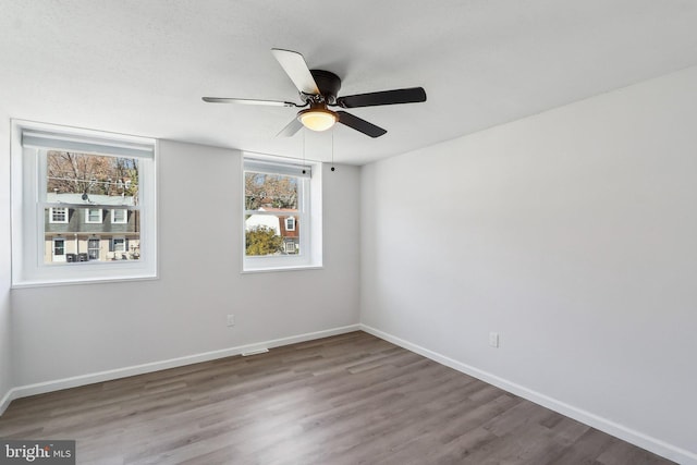 empty room featuring ceiling fan, baseboards, and wood finished floors