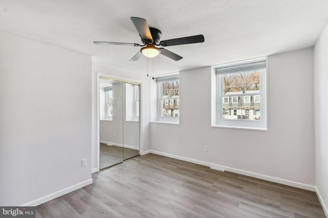 unfurnished bedroom featuring a closet, wood finished floors, a ceiling fan, and baseboards