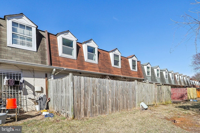 view of side of property with a shingled roof, a residential view, brick siding, and fence