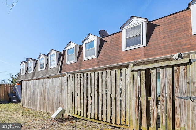 exterior space with a shingled roof and fence