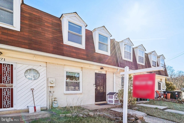 view of front of home with brick siding and roof with shingles