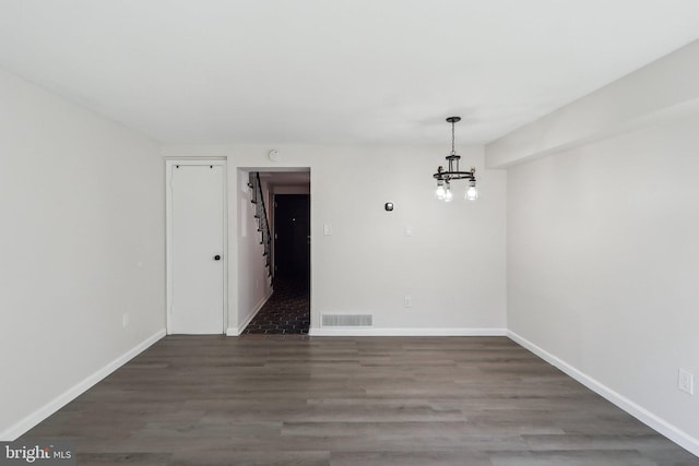 unfurnished dining area with a notable chandelier, wood finished floors, visible vents, and baseboards