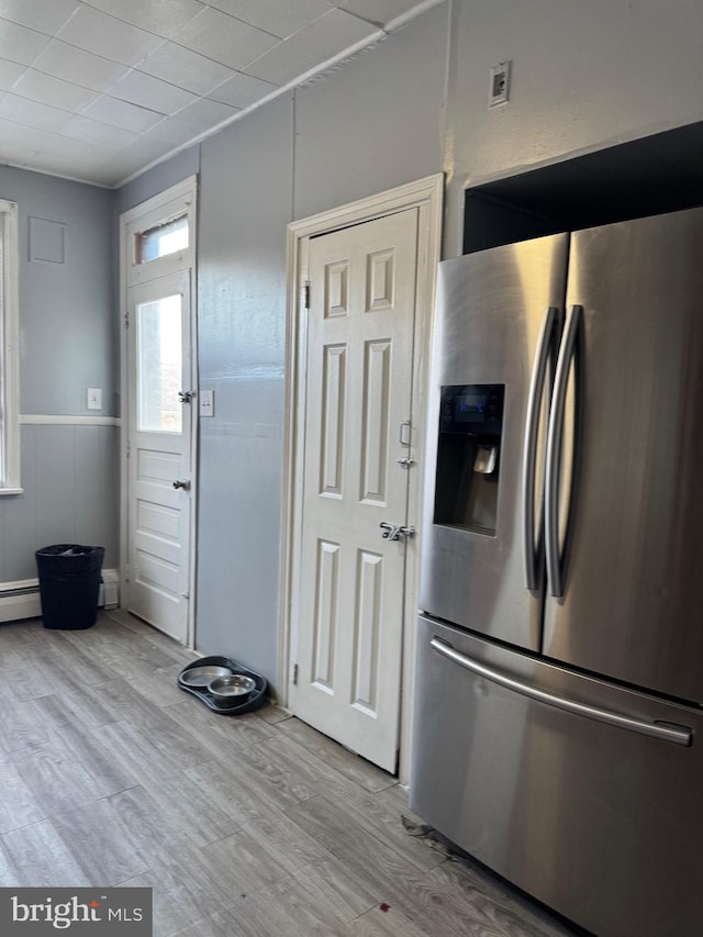 kitchen featuring light wood-style floors, a wainscoted wall, and stainless steel fridge