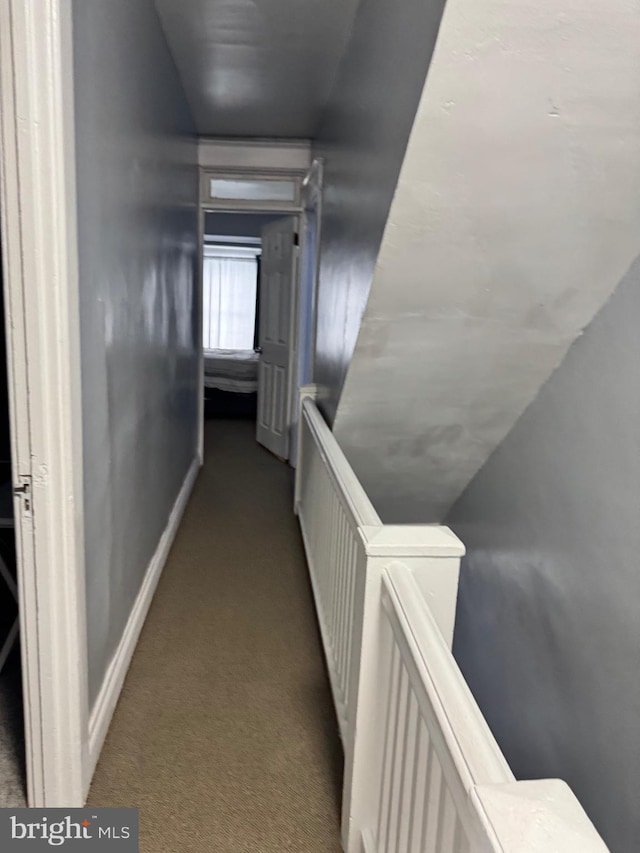 hall with baseboards, an upstairs landing, and light colored carpet