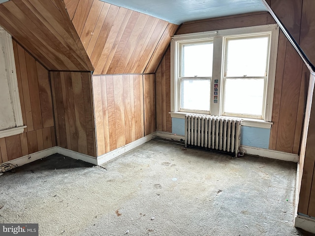 additional living space featuring lofted ceiling, radiator, and wooden walls