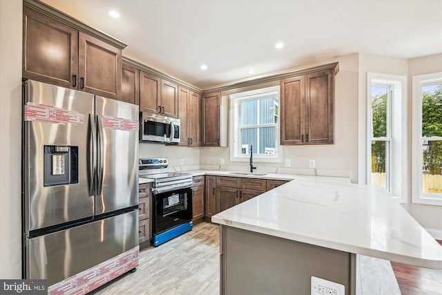 kitchen featuring appliances with stainless steel finishes, light stone countertops, sink, and plenty of natural light