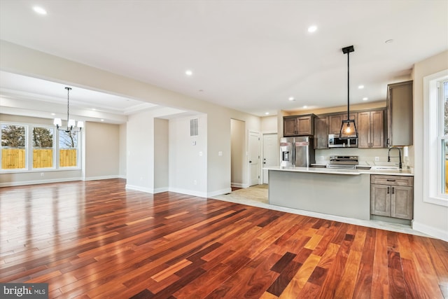 kitchen with sink, stainless steel appliances, decorative light fixtures, a chandelier, and light wood-type flooring