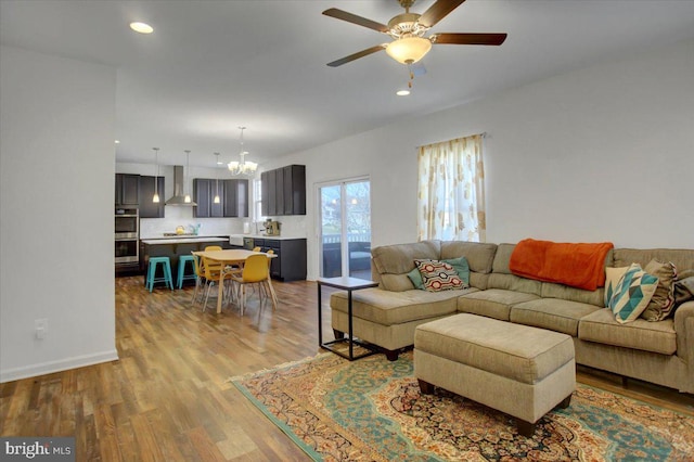 living room with ceiling fan with notable chandelier and light hardwood / wood-style floors