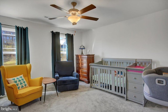 carpeted bedroom with a nursery area and ceiling fan