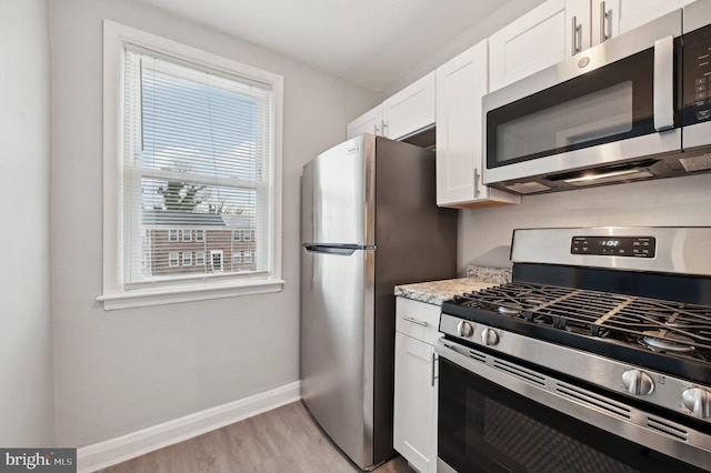 kitchen with appliances with stainless steel finishes, light hardwood / wood-style flooring, and white cabinets