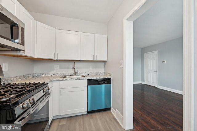 kitchen with sink, white cabinets, light stone counters, stainless steel appliances, and dark wood-type flooring